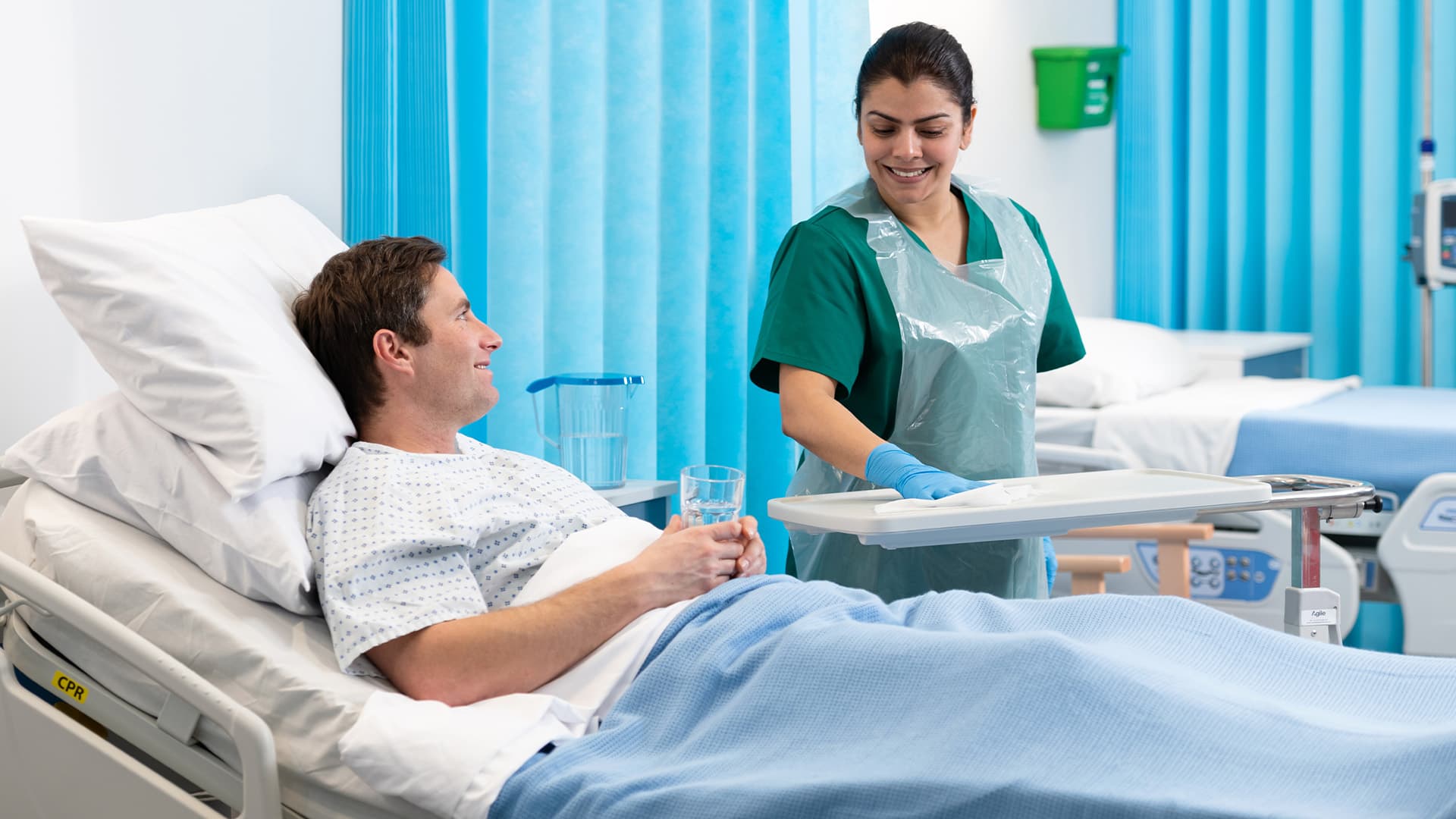 Nurse wiping patient tray table next to patient