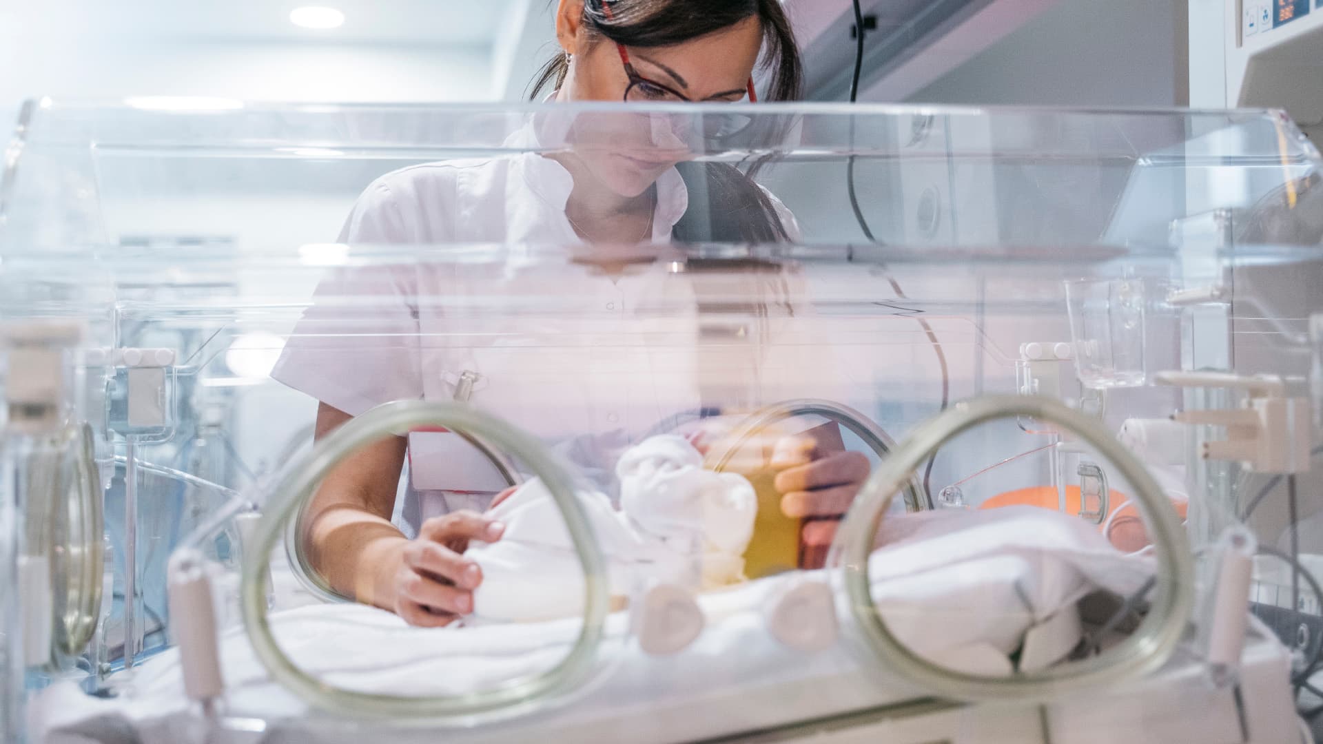 Nurse caring for baby in incubator
